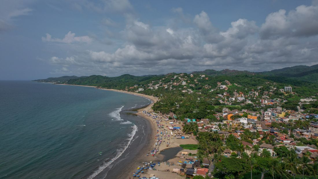 A coastal beach town wrapped in green hills