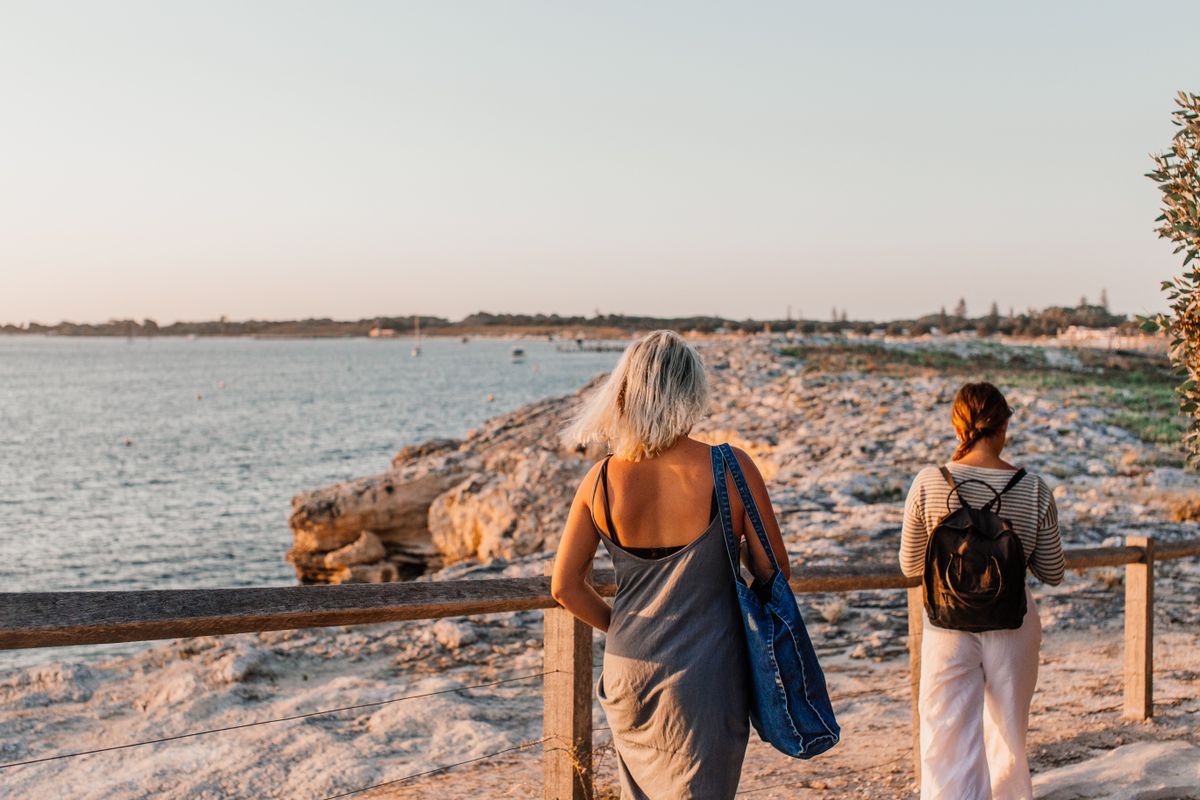 Two people on a coastal boardwalk at golden hour