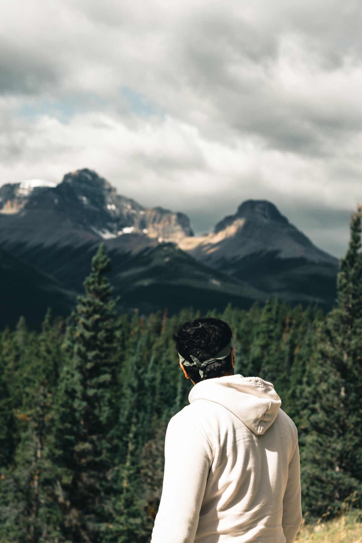 A person in a cream hoodie looking out over a mountain range